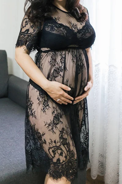 Une fille enceinte se tient près de la fenêtre vêtue d'un dr transparent — Photo