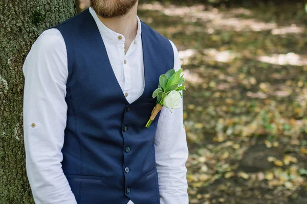 Kareli takım elbiseli yakışıklı, zarif sakallı damat ormandaki köprüde duruyor. Şık bir düğün damadı fotoğrafı. Köylü hipster portresi..
