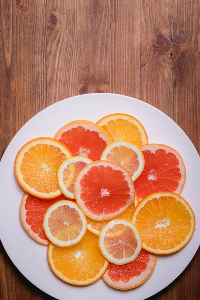 Orange grapefrukt och citron styckning i en platta på en trä bakgrund — Stockfoto