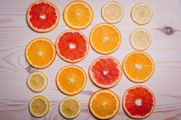Цитрусовые фрукты, разрезанные пополам - апельсины, лимоны, мандарины, грейпфруты на деревянном фоне — стоковое фото