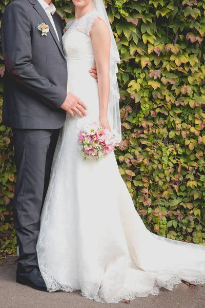 La novia y el novio están cerca de la pared verde —  Fotos de Stock