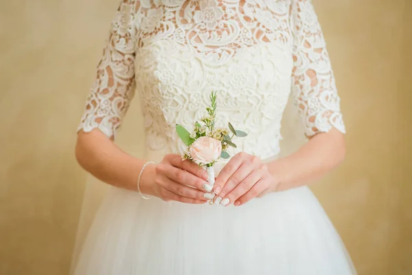 Boutonniere groom in the hands of the bride. Gentle hand of the bride boutonniere for the groom. — Stock Photo, Image