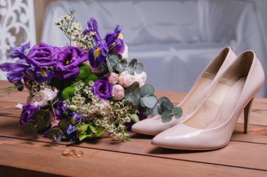 ahşap bir masa üzerinde bir düğün buket yeşil yaprakları, mor ve beyaz çiçekler, alyans