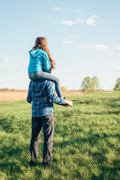 Feliz hombre sosteniendo a su pequeña hija en el cuello en el parque de verano — Foto de Stock