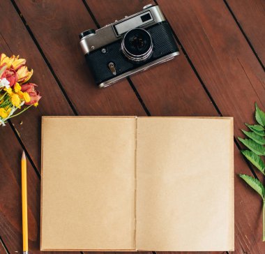 düz yatıyordu günlüğü. Ahşap arka plan üzerinde defter kağıt ve kamera Üstten Görünüm .