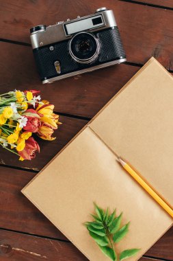 düz yatıyordu günlüğü. Ahşap arka plan üzerinde defter kağıt ve kamera Üstten Görünüm .