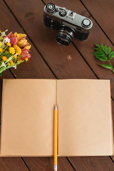 düz yatıyordu günlüğü. Ahşap arka plan üzerinde defter kağıt ve kamera Üstten Görünüm .
