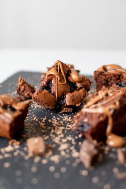 Vişneli browni yakın plan. Lezzetli bir vişneli kek siyah bir masanın üzerinde yatıyor. Çikolata serpiştirilmiş Brownie. Brownie evde pişirdi. Brownie DIY. Yukarıdan görüntüle.