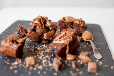 Vişneli browni yakın plan. Lezzetli bir vişneli kek siyah bir masanın üzerinde yatıyor. Çikolata serpiştirilmiş Brownie. Brownie evde pişirdi. Brownie DIY. Yukarıdan görüntüle.