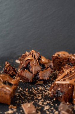 Vişneli browni yakın plan. Lezzetli bir vişneli kek siyah bir masanın üzerinde yatıyor. Çikolata serpiştirilmiş Brownie. Brownie evde pişirdi. Brownie DIY. Yukarıdan görüntüle.