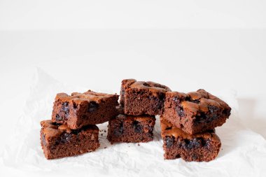 Vişneli browni yakın plan. Lezzetli bir vişneli kek kağıt üzerinde beyaz bir masanın üzerinde yatıyor. Çikolata serpiştirilmiş Brownie. Brownie evde pişirdi. Brownie DIY. Yukarıdan görüntüle.