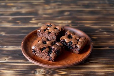 Vişneli browni yakın plan. Lezzetli vişneli brownie ahşap bir masada bir tabakta yatıyor. Çikolata serpiştirilmiş Brownie. Evde pişmiş 