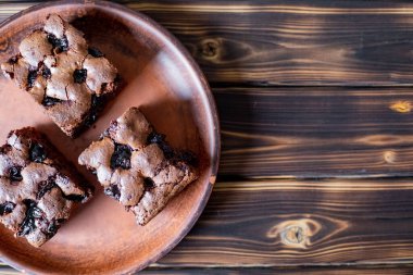 Vişneli browni yakın plan. Lezzetli vişneli brownie ahşap bir masada bir tabakta yatıyor. Çikolata serpiştirilmiş Brownie. Evde pişmiş 