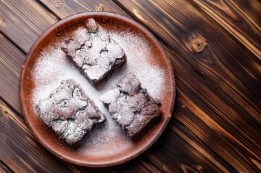 Vişneli browni yakın plan. Lezzetli vişneli brownie ahşap bir masada bir tabakta yatıyor. Çikolata serpiştirilmiş Brownie. Evde pişmiş 