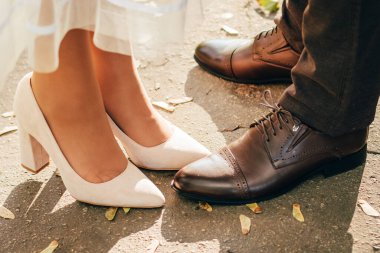 Gelinin ve damadın ayakları yakın çekim. Gelin ve damat yürüyüşe çıktı. Gelin ve damat kullanılmış düğün ayakkabılarıyla. Dinlenmiş çift. Yakın plan düğün ayakkabıları.