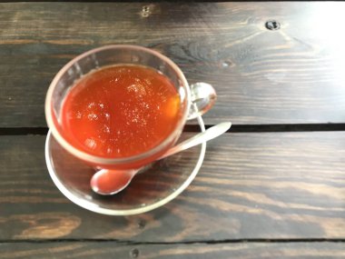 Büyük ağaç refleksini yüzeye odaklayan limon çayının diğer kısmı bulanık. Çay bardağı ahşap masanın sol tarafında. Sonra sağ taraf fotokopi için boş..