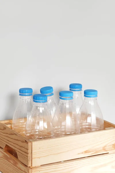 Plastic bottles with blue caps for recycling in a wooden box.