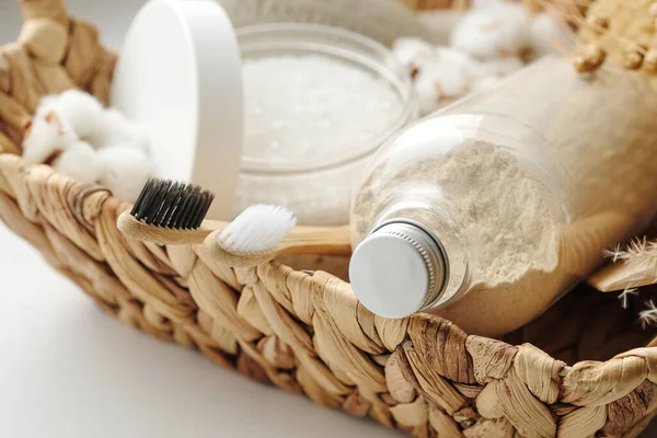 Spa and wellness cosmetic products:body scrub,beech toothbrushes,sea bath salt,soap, wooden hair comb in a wicker basket — Stockfoto