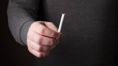 Elinde sigara tutan bir erkek. Sigara içmeyi bırak. Kötü alışkanlığı bırak, sağlıklı yaşam tarzı kavramını. Sigara içmek yasak. Yanlış yaşam biçimini seçmeyin.