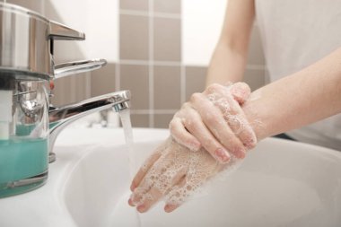 Musluğun altında sabunla ellerini yıkamak. Corona virüsünün önlenmesi için su, Coronavirus bulaştırmamak için hijyen. Hijyen konsepti, hijyen, temizlik, temizlik, temizlik, dezenfekte, hijyenik insan. 