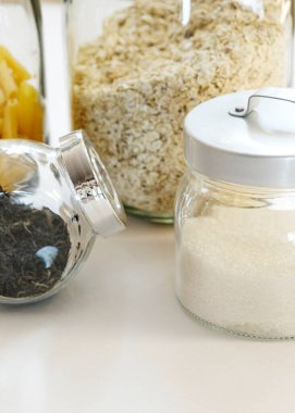 Makarna, yulaf ezmesi, kraker, şeker ve çay cam kavanozlarda, beyaz arka planda mutfaklarda, bozulmaz ürünlerde. Düzenli ev sade stil depolama plastik yok, sıfır atık.