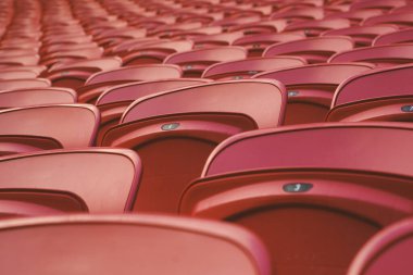 Boş bir stadyumda boş kırmızı plastik koltuklar. Tribünlerde seyirciler için bir sürü boş koltuk var. Futbol taraftarları için boş plastik sandalyeler.
