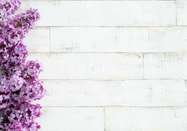 Açık arkaplanda bir ağacı taklit eden parlak, mor bir leylak. Ahşap zemin, dallar ve arka planda duran leylak çiçekleri. Dekor için fotofon