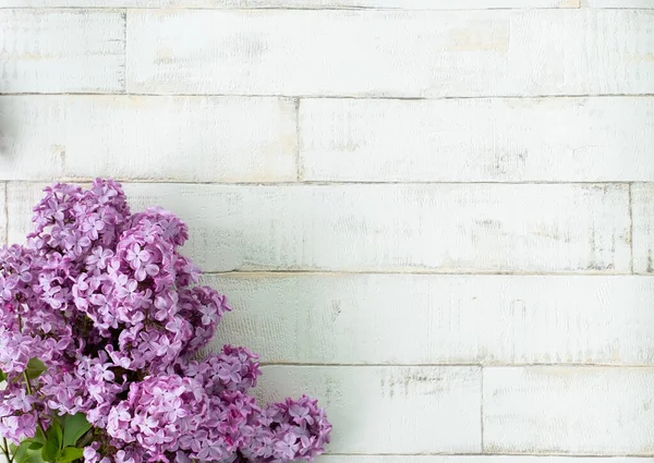 Açık arkaplanda bir ağacı taklit eden parlak, mor bir leylak. Ahşap zemin, dallar ve arka planda duran leylak çiçekleri. Dekor için fotofon