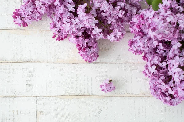 Açık arkaplanda bir ağacı taklit eden parlak, mor bir leylak. Ahşap zemin, dallar ve arka planda duran leylak çiçekleri. Dekor için fotofon