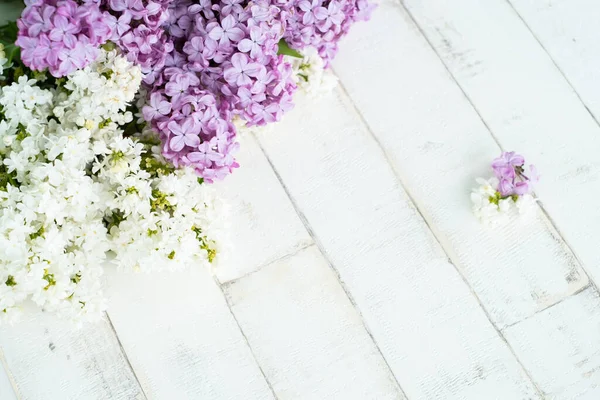 Açık arkaplandaki parlak mor ve beyaz leylak bir ağacı taklit ediyor. Ahşap zemin, dallar ve arka planda duran leylak çiçekleri. Dekor için fotofon