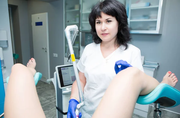 Beyaz önlüklü, siyah saçlı jinekolog ve jinekolog muayenehanesindeki mavi steril eldivenli jinekolog hastanın intravaginal ultrasonunu yapıyor. Üreme ilaçları, jinekoloğa planlanan ziyaret.