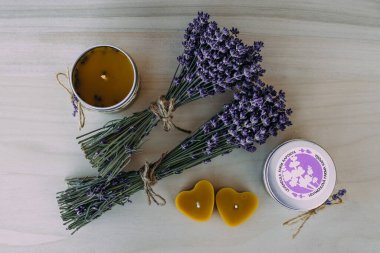 İki kurutulmuş lavanta demeti ve ahşap dokuda el yapımı balmumu mumlarının yatay düzeni
