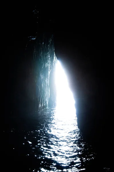 Light at the end of tunnel assimetrical shape with water surface in the front . Way out of seacave