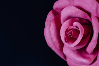 Siyah arka planda, dev pembe el yapımı foamiran çiçeği. Yatay yerleşim planı. Sol taraftaki metin boşluğu