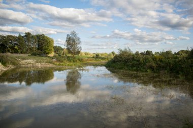 Gün batımında kırsal kesimdeki bir nehirde muhteşem bulutların yansıması.