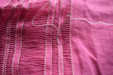 Pembe keten üzerine beyaz ipliklerle işlenmiş el yapımı nakış.