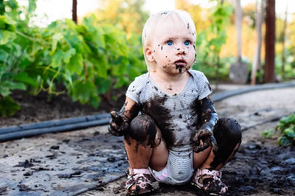 child playing in the mud on the street
