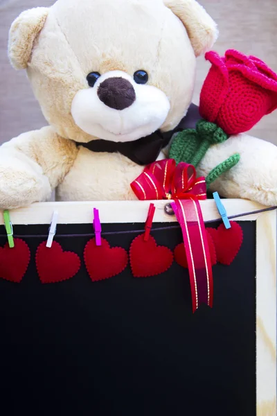 Zabawka ładny Miś ściskając czerwona róża w jej ramiona i blackbo — Zdjęcie stockowe