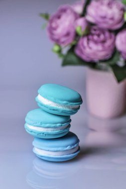 Bir yığın pembe çiçeğe karşı üç mavi badem kurabiyesi.