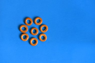 Küçük mavi bir arka plan üzerinde rulo. Kalachi, bir çiçek şeklinde ortaya koydu. Şekerlemeler kalachi. Tatlı, kurutma, kek