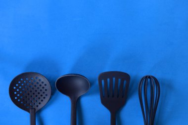 Mavi bir arka plan üzerinde siyah yemekleri. Üst üste çerçevenin alt mutfak aksesuarları.