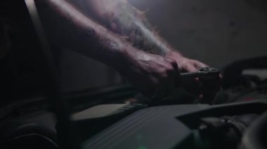 Tamirci garajdaki araba motoru üzerinde çalışıyor.