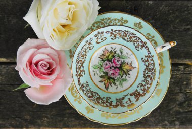 Dekoratif bir natürmort porselen çay fincanı ve tabağı gül, yıpranmış ahşap rustik bir arka plan ile. Bir paragraf Çin collectable başlıklı, 