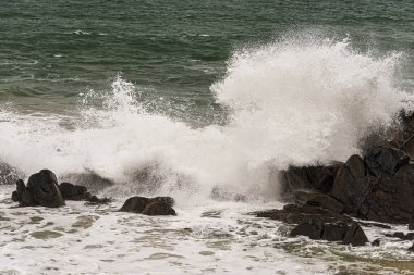 Kızgın dalgalar bir yaz fırtınası sırasında sahildeki kayalara çarpar. 