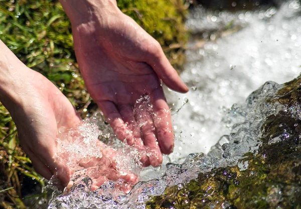 Bir dağ nehrinde hızlı akan su. Adam elleriyle su alıyor..