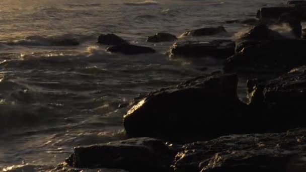Mer Caspienne au coucher du soleil. Des vagues courent sur un rivage rocheux .