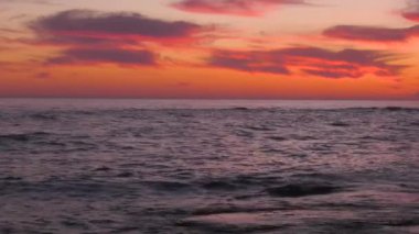 Günbatımında Hazar Denizi. Dalgalar kayalık bir kıyıya vurur.