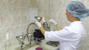 Bakteriyoloji laboratuvarı. Biyokimyasal analiz. Laboratuvar asistanı bakteriyolojik kültürleri bir petri kabına eker..