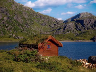 Kapalı ot çatılı evi. Geri kalan çim ile büyümüş house Dağları ile çevrili.