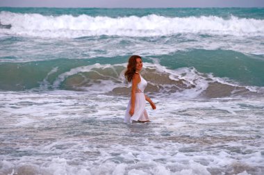 Kız okyanus arka plan üzerinde. Karayip denizin dalgaları beyaz elbiseli ince, güneşten kız yürüyor.